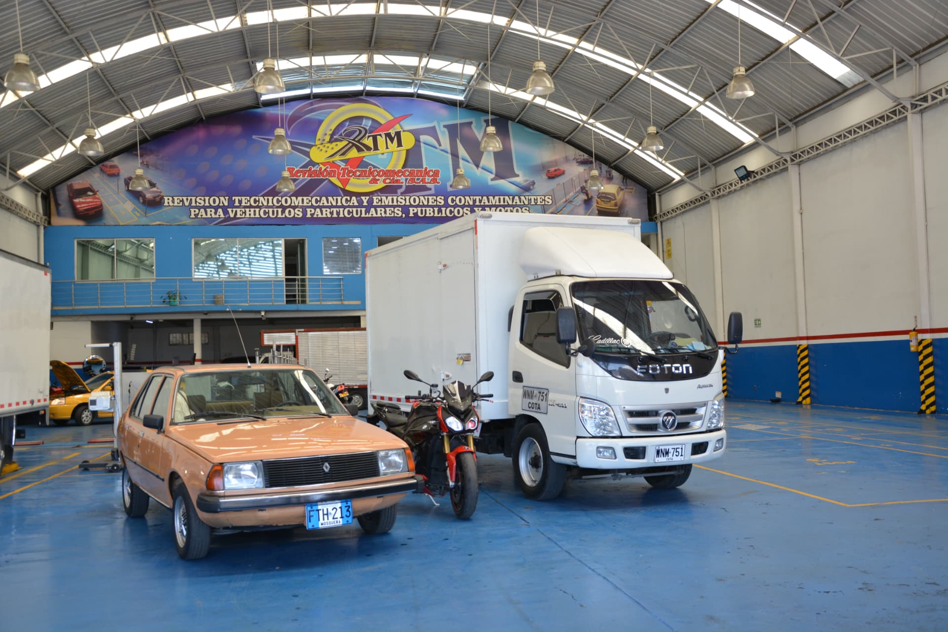 Camión de carga, moto y automóvil en las instalaciones de Revisión Técnico Mecánica y CÍA S.A.S